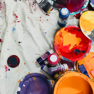 Buckets of paint on a floor covering.