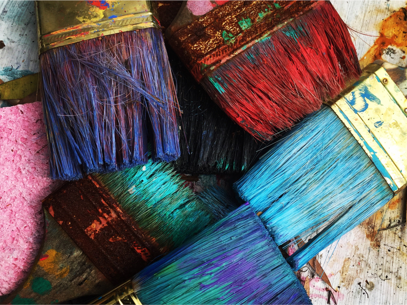 Paint brushes in a pile, all different colours.