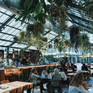 A group of people sitting at a table in a greenhouse-like restaurant.